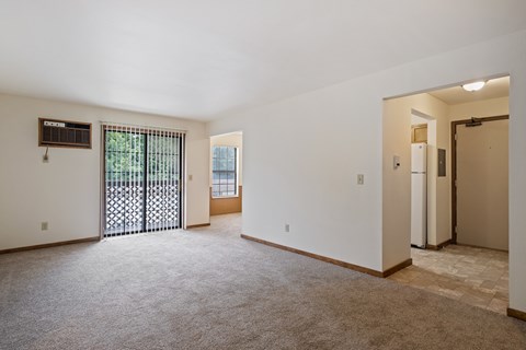 A spacious room with a sliding glass door and a carpeted floor.