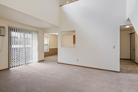 A large, empty room with a carpeted floor and white walls.
