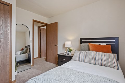 A bedroom with a bed, nightstand, and mirror.