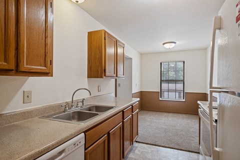 A kitchen with brown cabinets and a white dishwasher.