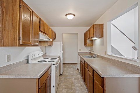 A kitchen with white appliances and wooden cabinets.