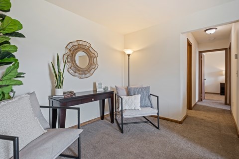 A living room with a grey couch, a wooden table, and a mirror on the wall.