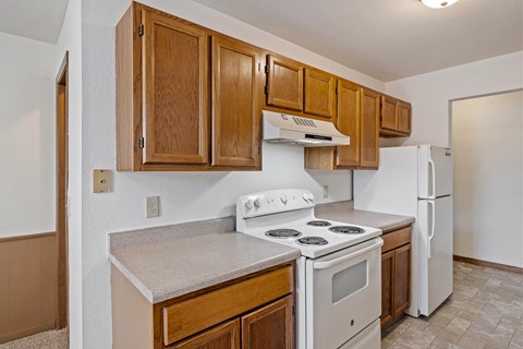A kitchen with white appliances and wooden cabinets.