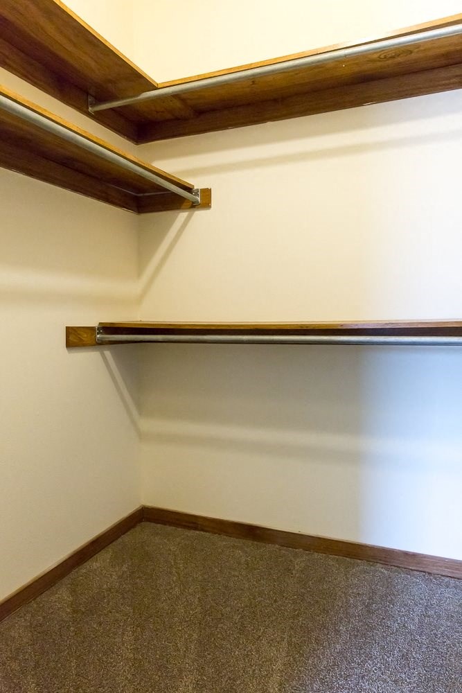 a walk in closet with a wooden railing on the wall