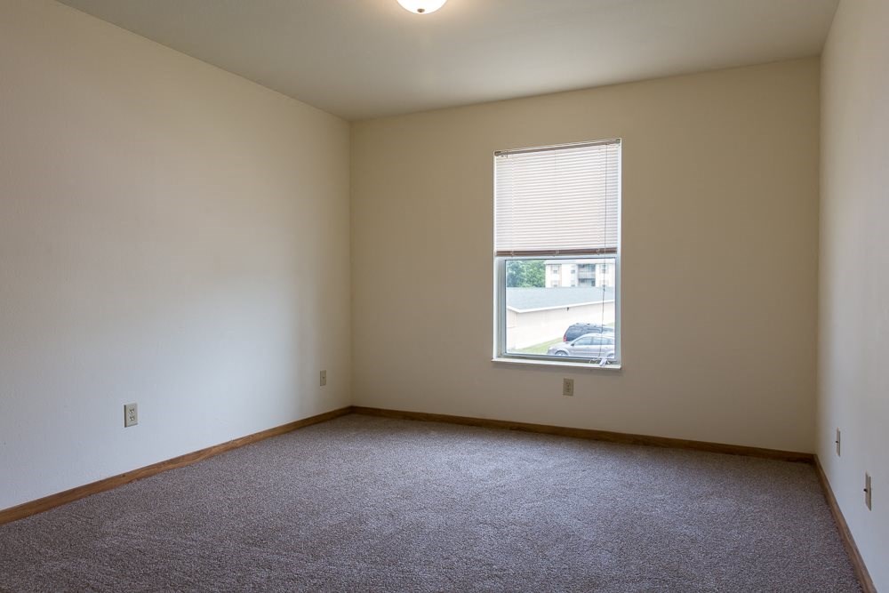 an empty living room with a window and carpet