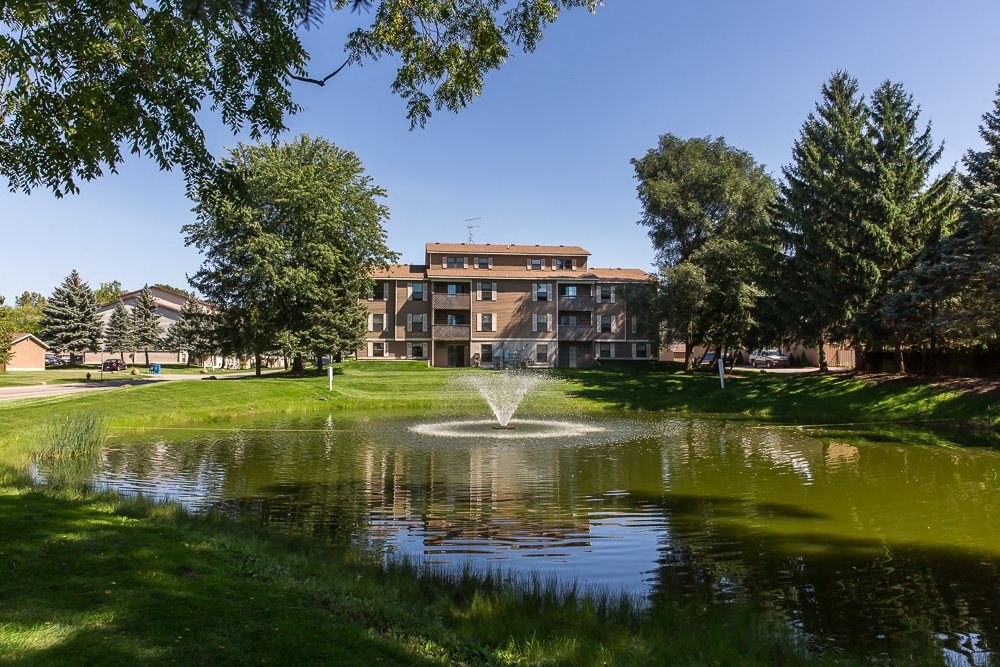a fountain in the middle of a pond in front of a building