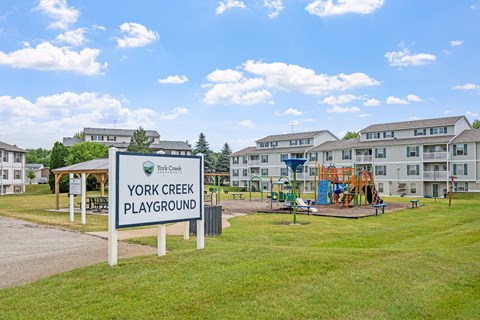 A playground sign for York Creek Playground stands in front of a building.