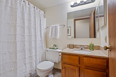 A white toilet sits under a white shower curtain in a bathroom.