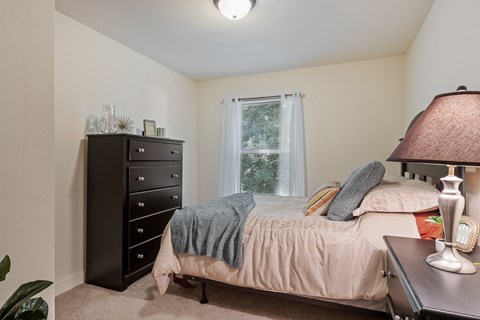 A bedroom with a bed, dresser, and window.