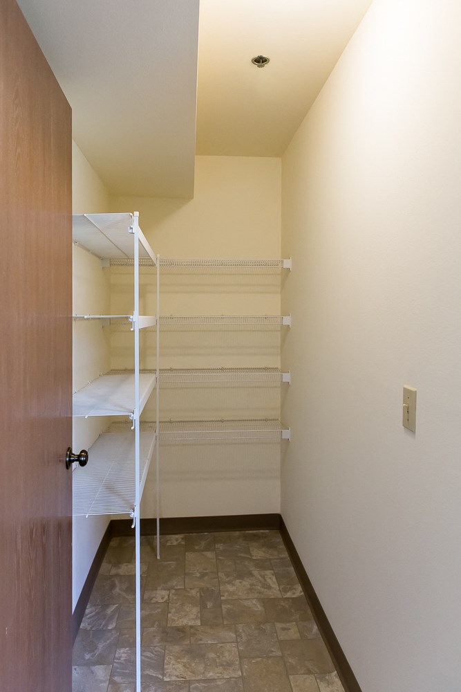 a walk in closet with white shelves and a door