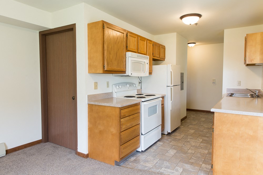 a kitchen with white appliances and wooden cabinets and a refrigerator