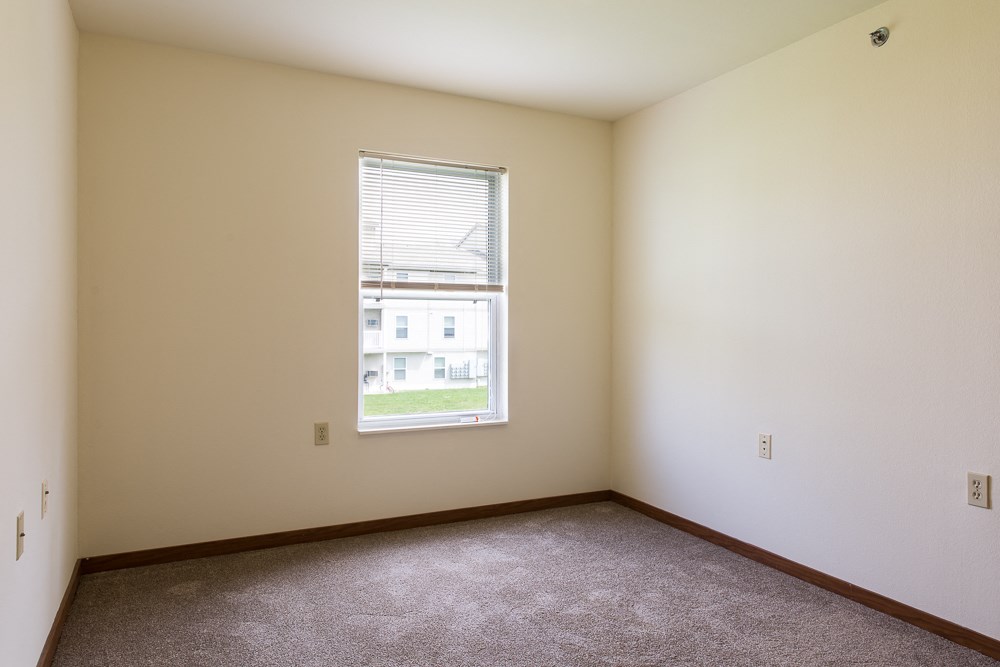 an empty room with a window and carpet