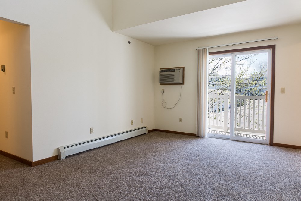 an empty living room with a door to a balcony