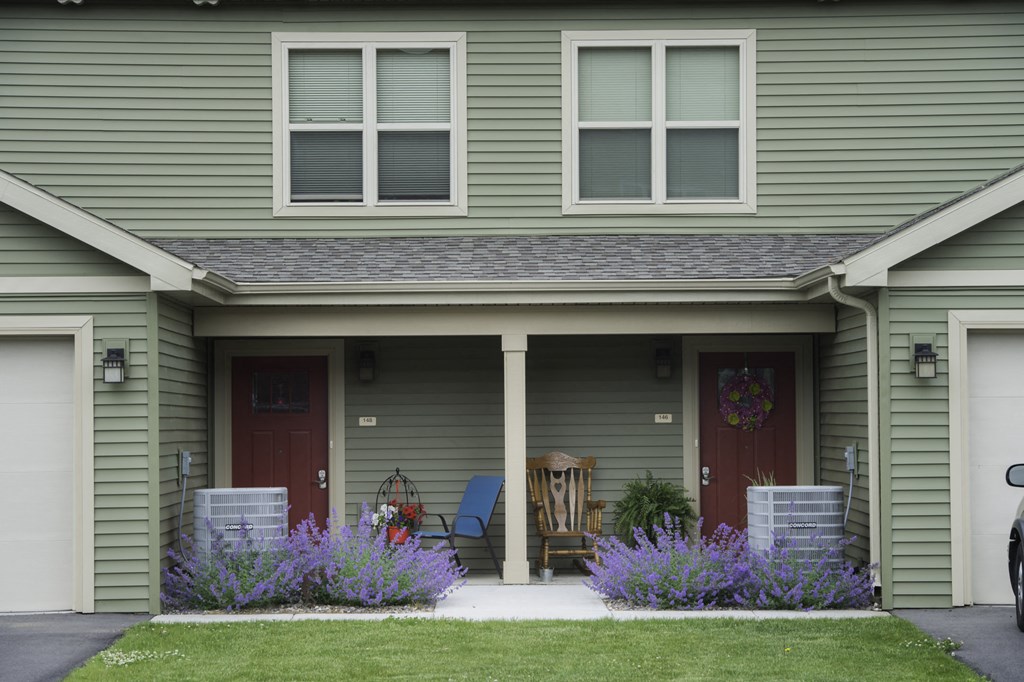 the front of a green house with purple flowers