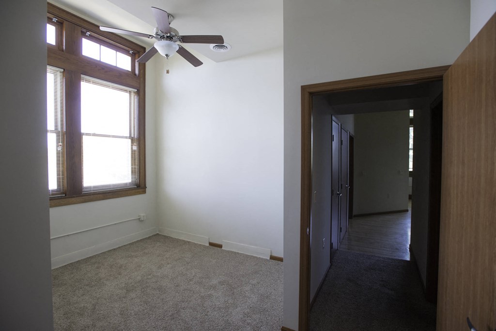 a bedroom with a ceiling fan and a door to a hallway