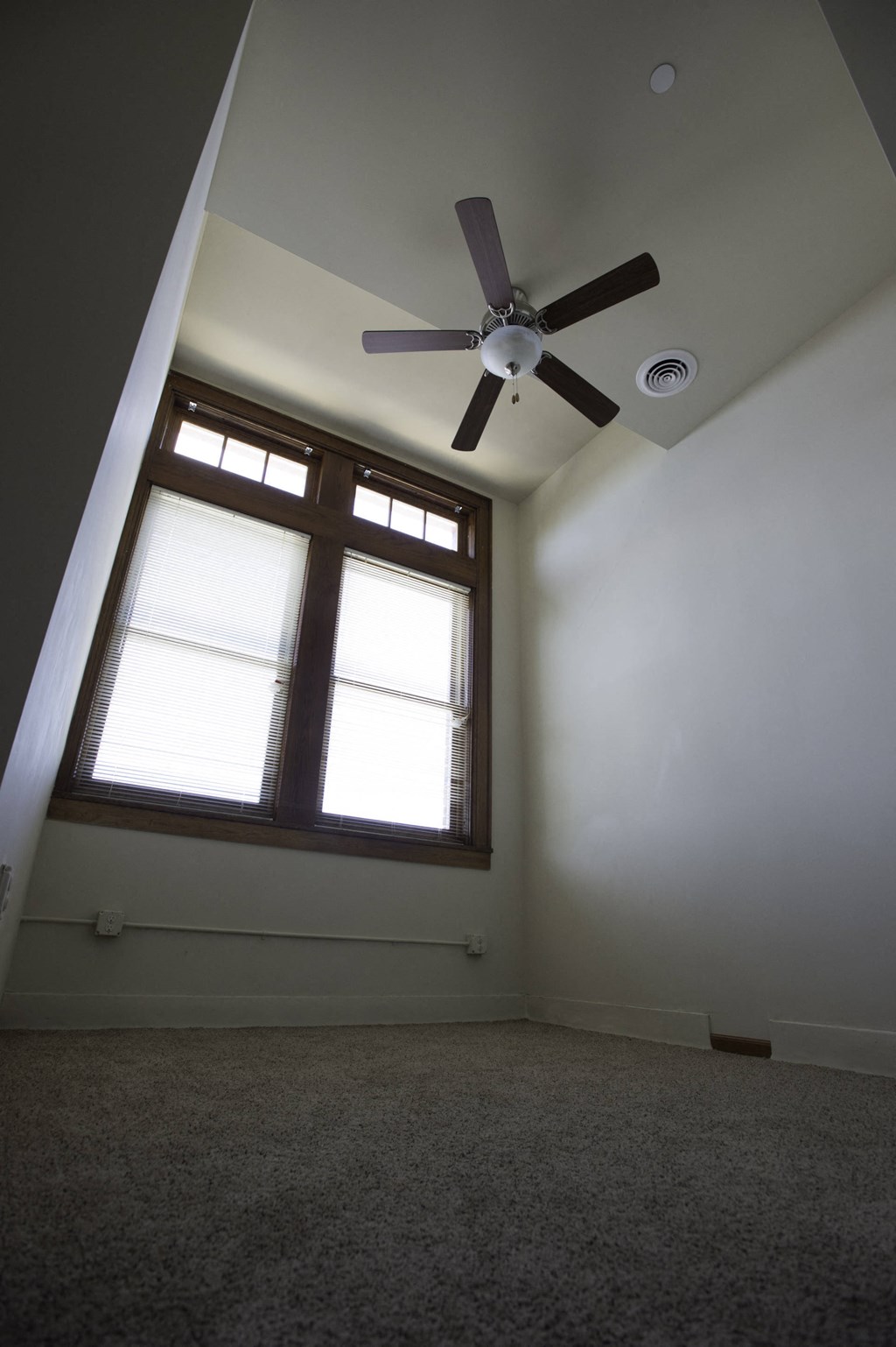 an empty room with a large window and a ceiling fan