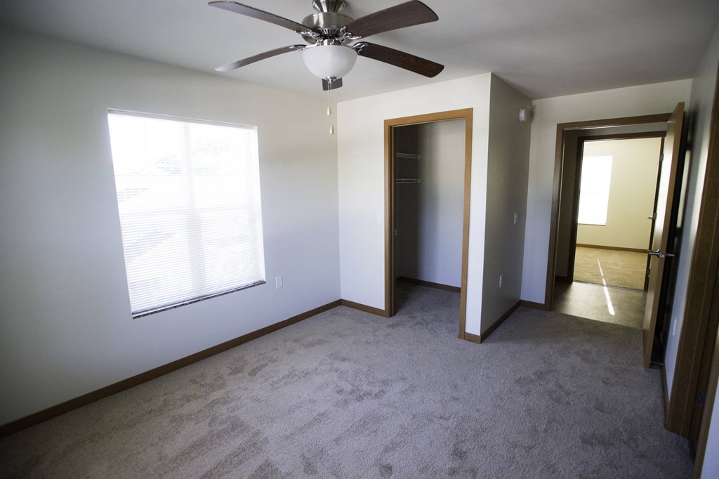 an empty living room with a ceiling fan and a window