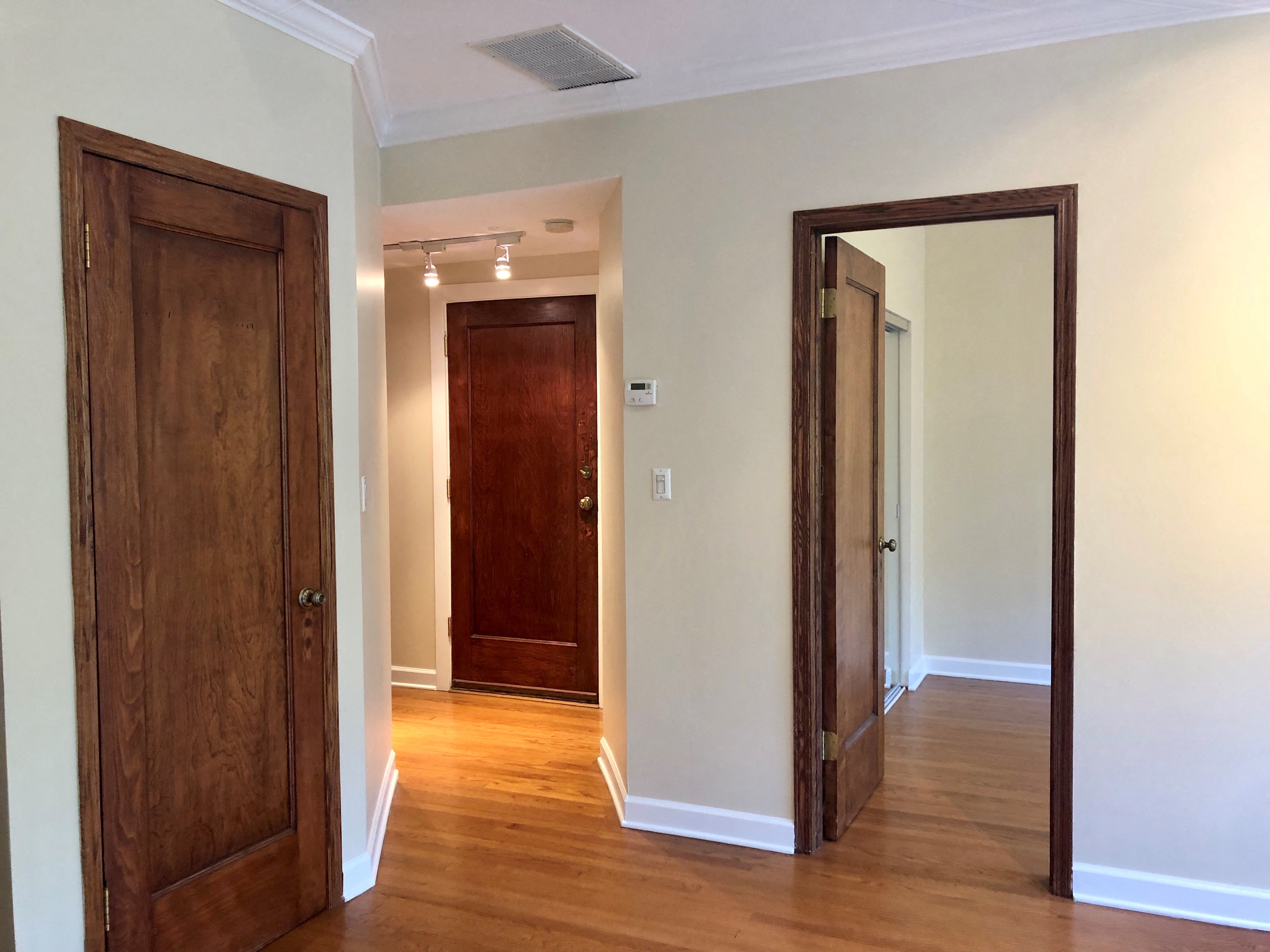 a hallway with two wooden doors and a door to a closet