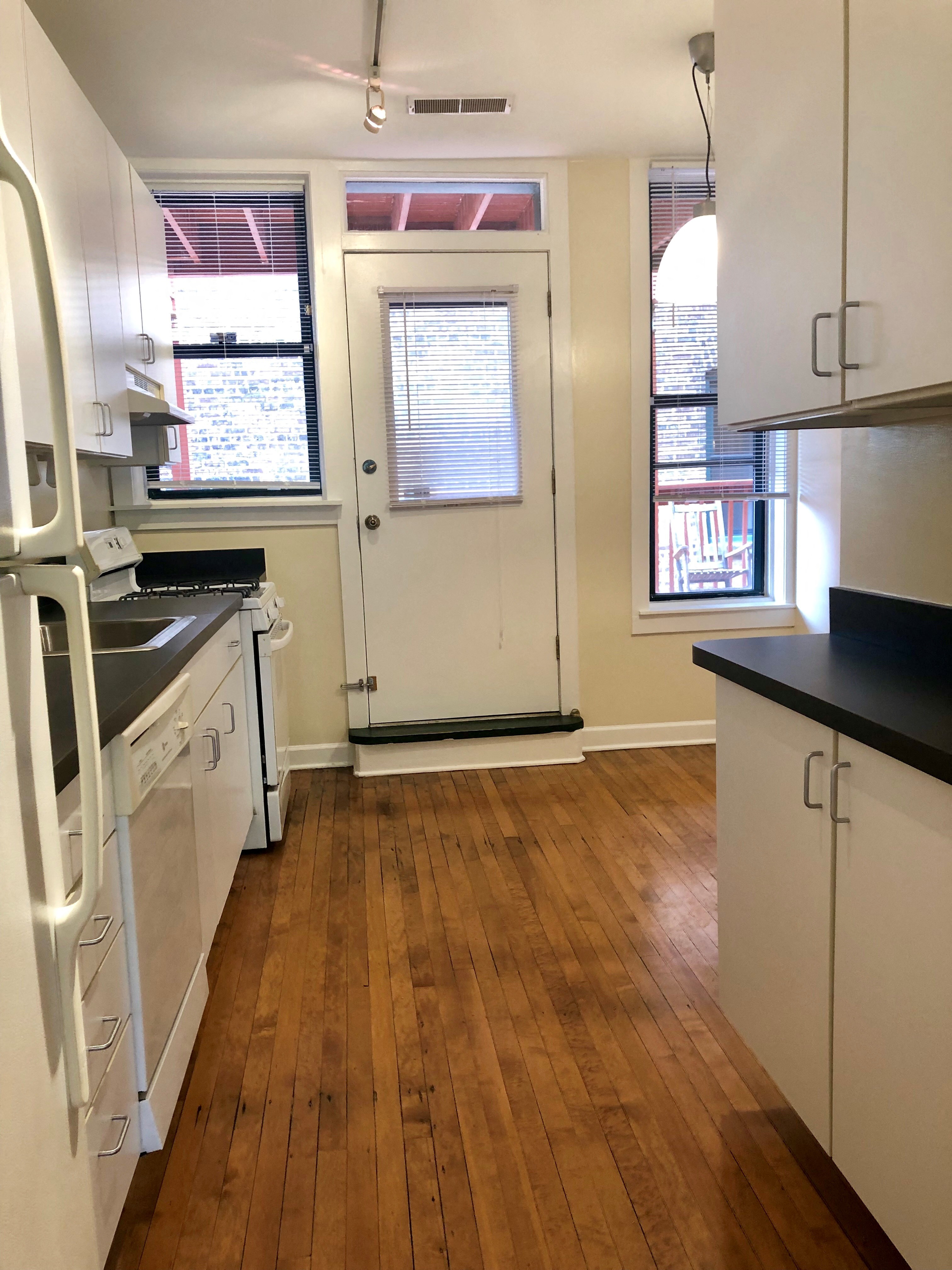 a kitchen with a wooden floor and white cabinets