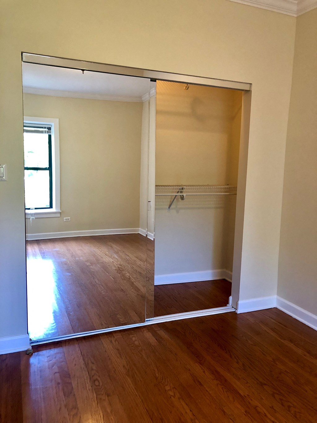 an empty bedroom with a closet and a wood floor