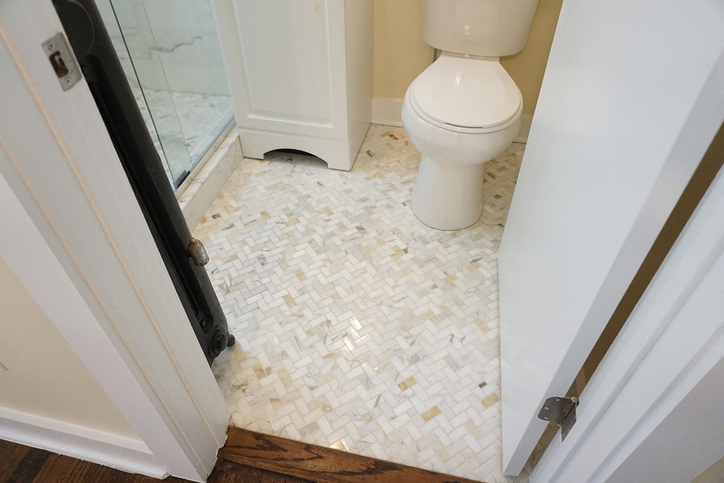the bathroom has a white tile floor and a white toilet