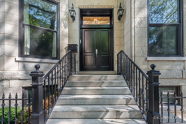 the front of a building with a black door and stairs