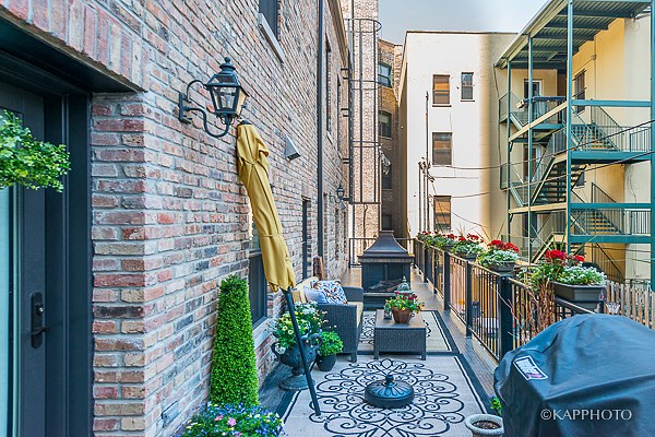 a small courtyard with a brick wall and plants and an umbrella