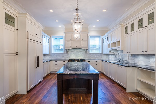 a large kitchen with white cabinets and a black counter top