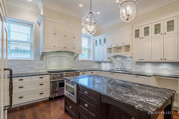 a large kitchen with marble counter tops and white cabinets