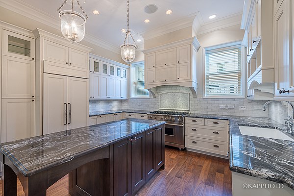 a large kitchen with marble counter tops and white cabinets
