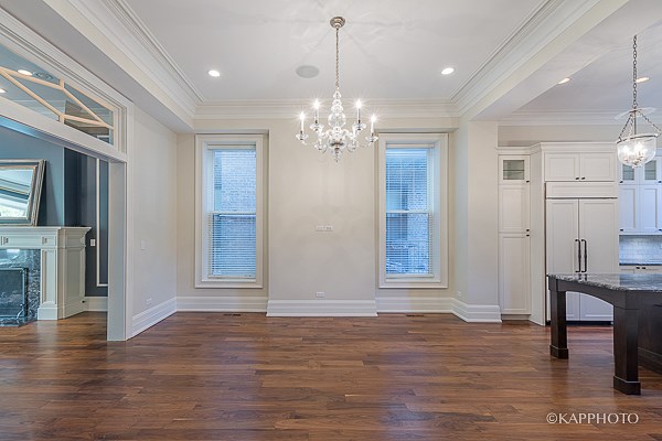 an empty living room with a kitchen and a chandelier
