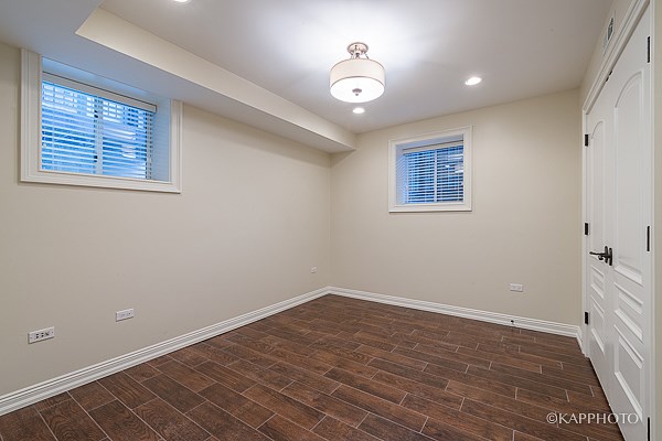 an empty room with wood flooring and two windows
