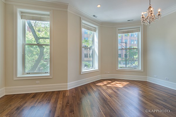 an empty living room with a chandelier and three windows