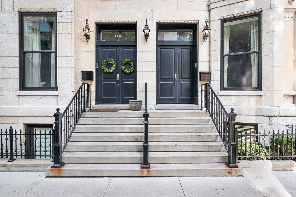 two black doors on a white building with stairs