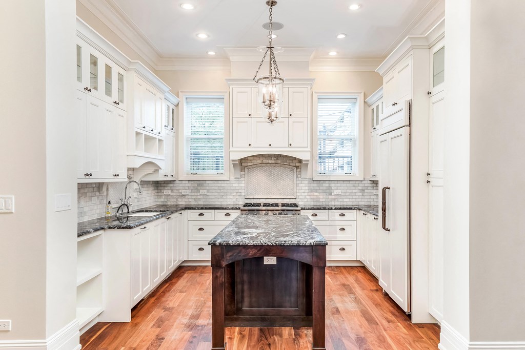 a kitchen with white cabinets and a marble counter top