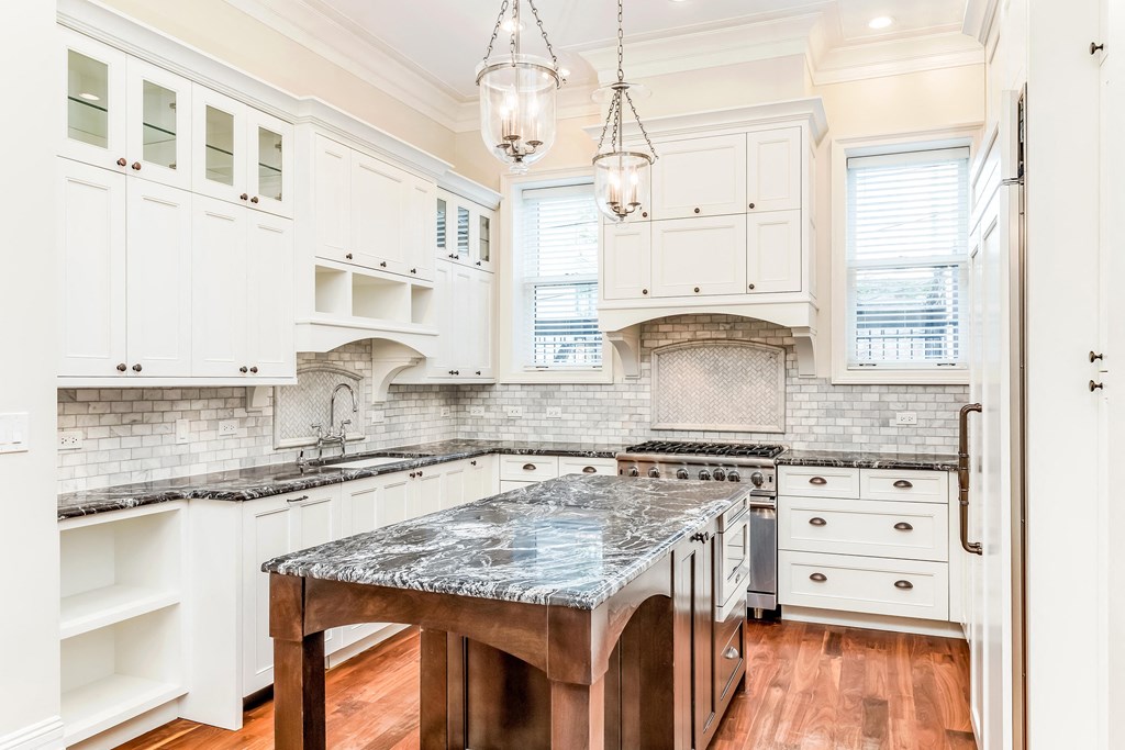 a kitchen with white cabinets and a marble counter top