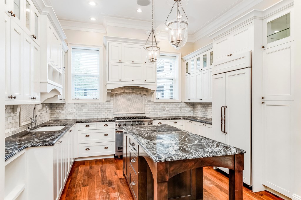a large kitchen with marble counter tops and white cabinets