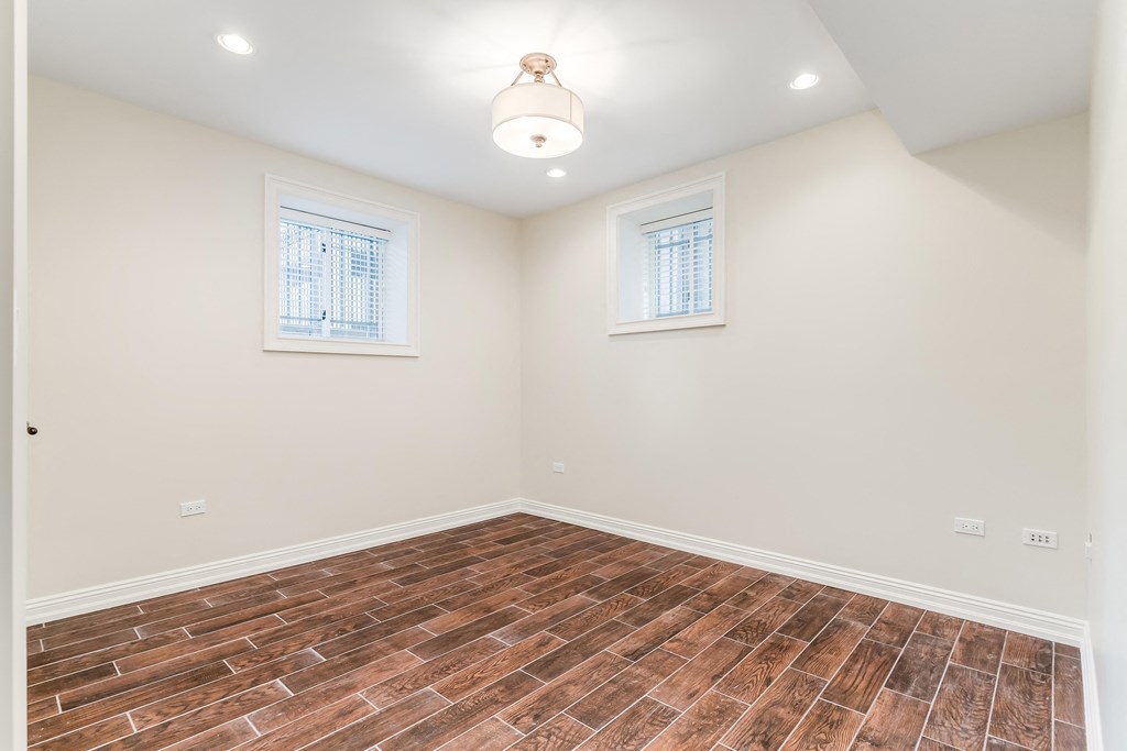 an empty room with wood flooring and two windows