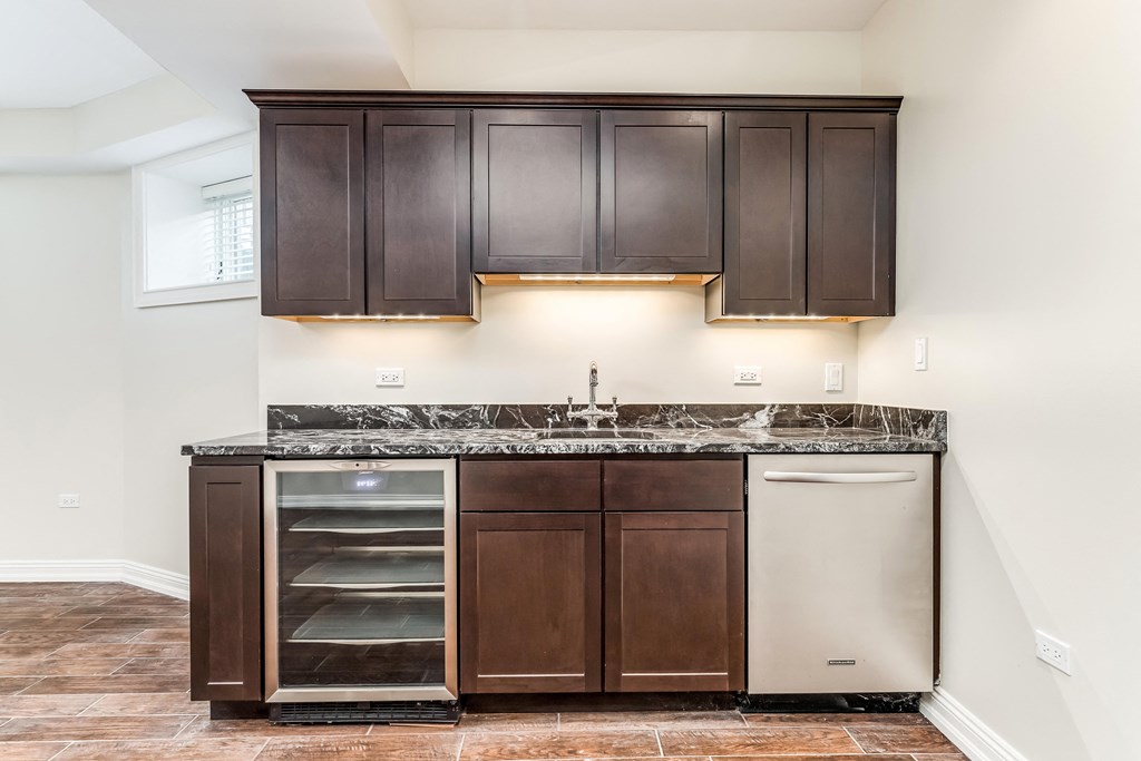 an empty kitchen with dark cabinets and a stainless steel dishwasher
