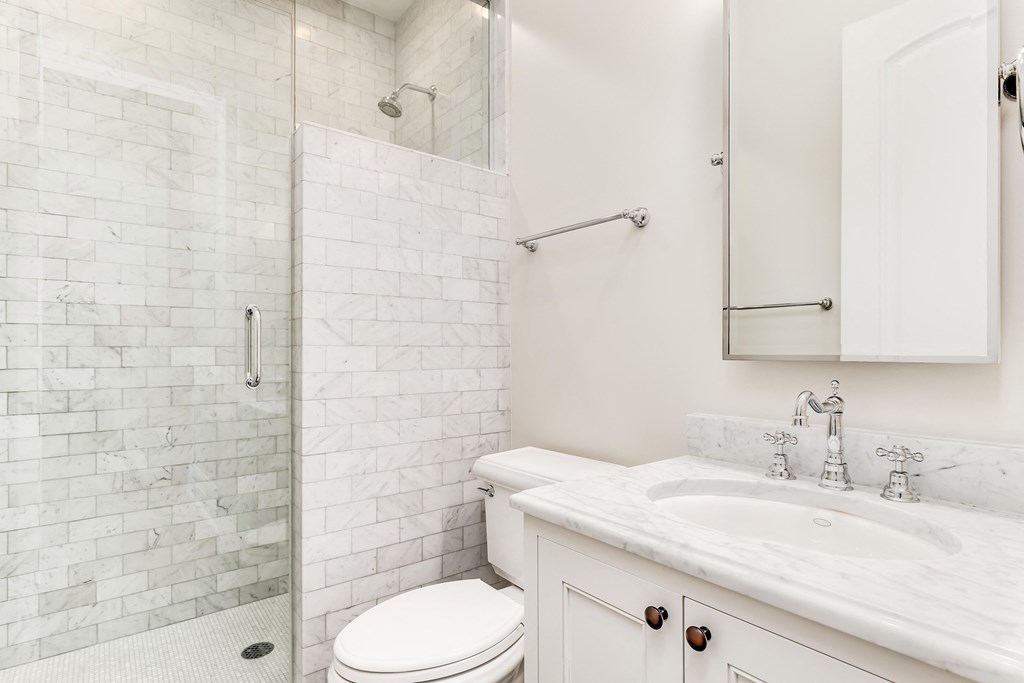 a white bathroom with a shower and a sink and a toilet