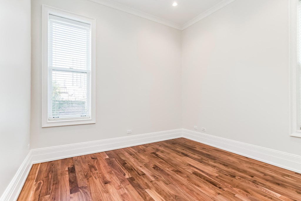 an empty room with wood flooring and a window