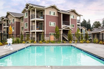 Pool with lounge chairs and apt buildings Vancouver, Washington | Copper Lane Apartments - Photo Gallery 7