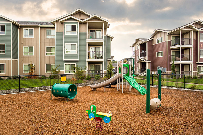 Playground with grass by apt buildings  Vancouver, WA 98684 | Copper Lane Apartment Homes