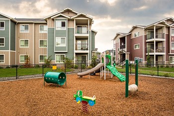 Playground with grass by apt buildings  Vancouver, WA 98684 | Copper Lane Apartment Homes - Photo Gallery 13