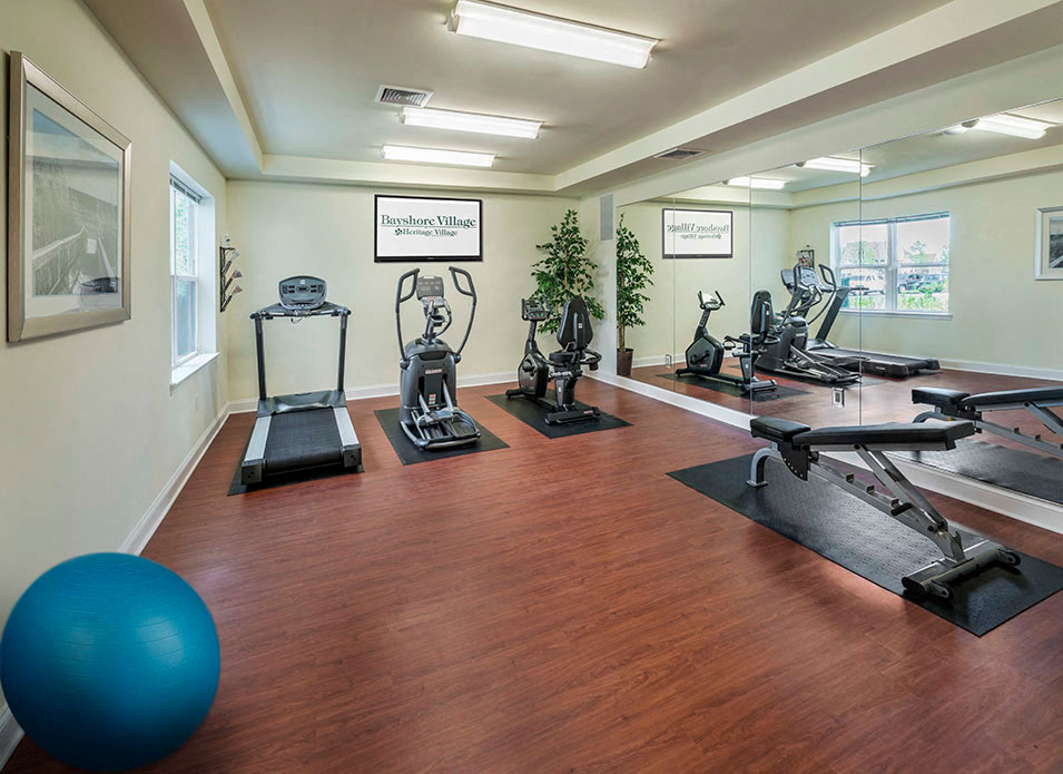 a gym with cardio equipment and weights on a wooden floor
