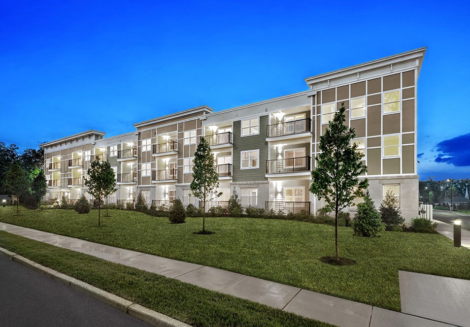 an exterior rendering of a large apartment building at dusk