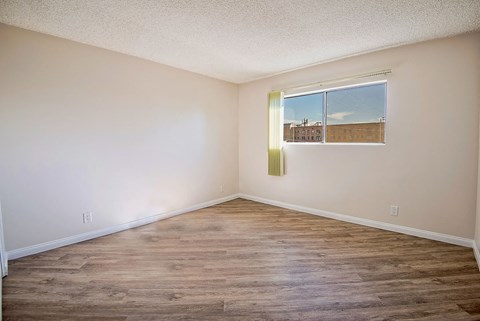 an empty room with a window and wood floors