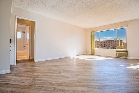 an empty living room with a large window and wood floors