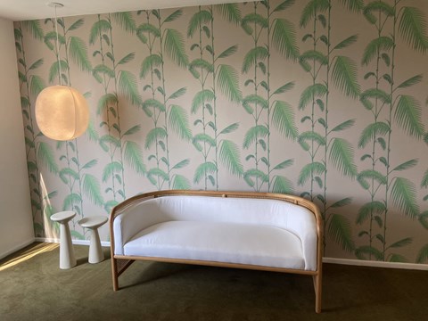a white couch in a room with a wallpaper with palm trees