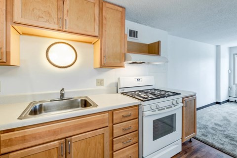 A kitchen with wooden cabinets and a white stove top oven.